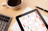 Workplace with tablet pc showing calendar and a cup of coffee on a wooden work table close-up.jpeg